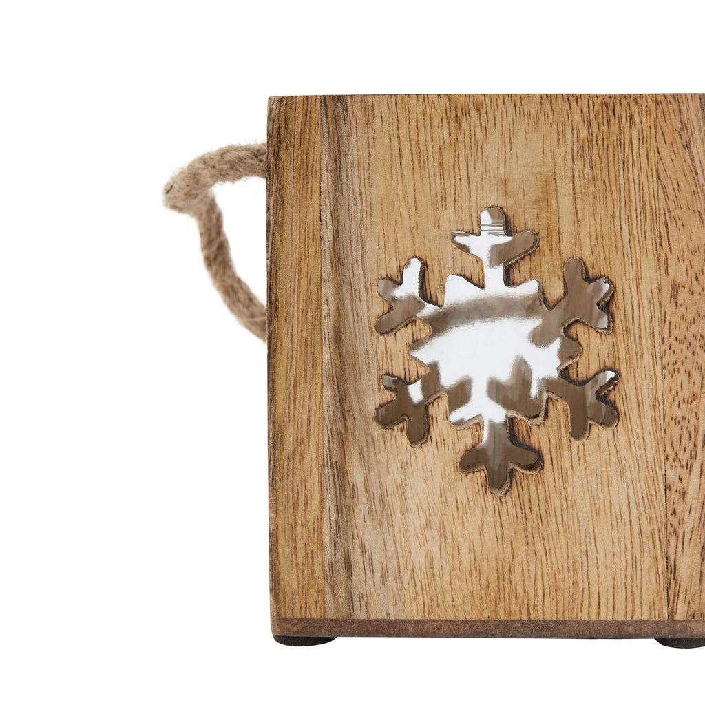 Handcrafted wooden snowflake tealight holder with glass accents, casting warm winter glow in rustic brown tones. by RoomLondon at brixbailey.com