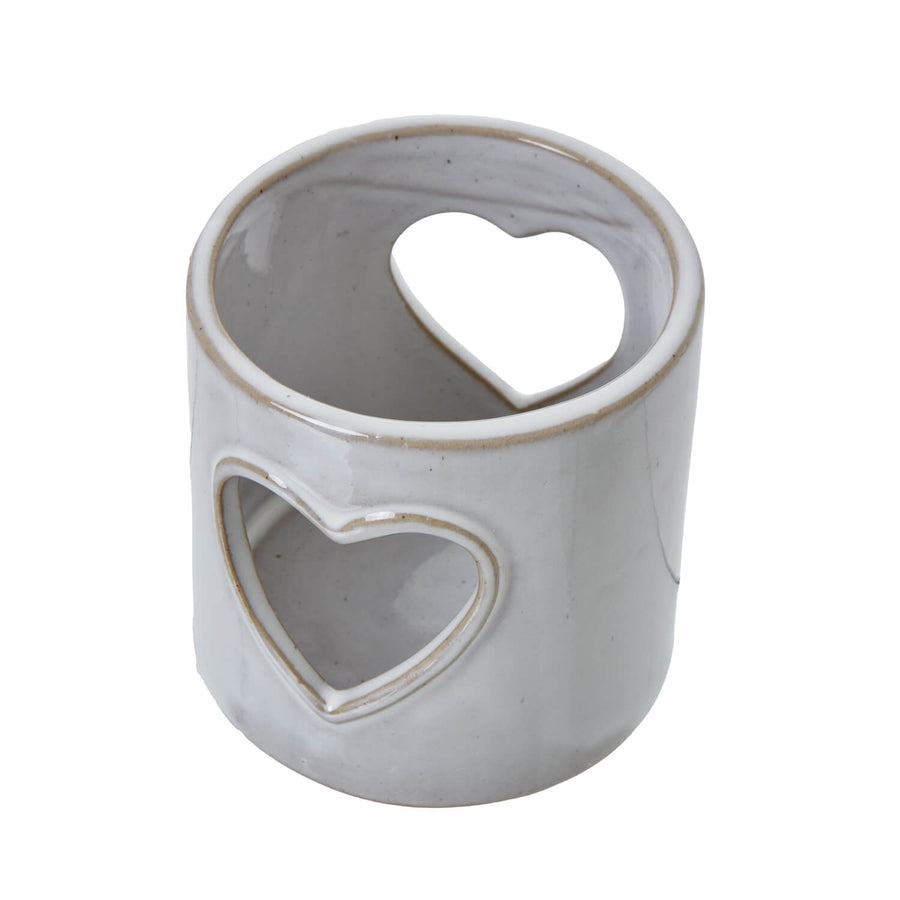 White ceramic tealight holder with heart cutouts, casting romantic shadow patterns for cozy ambiance. by Sostter at brixbailey.com