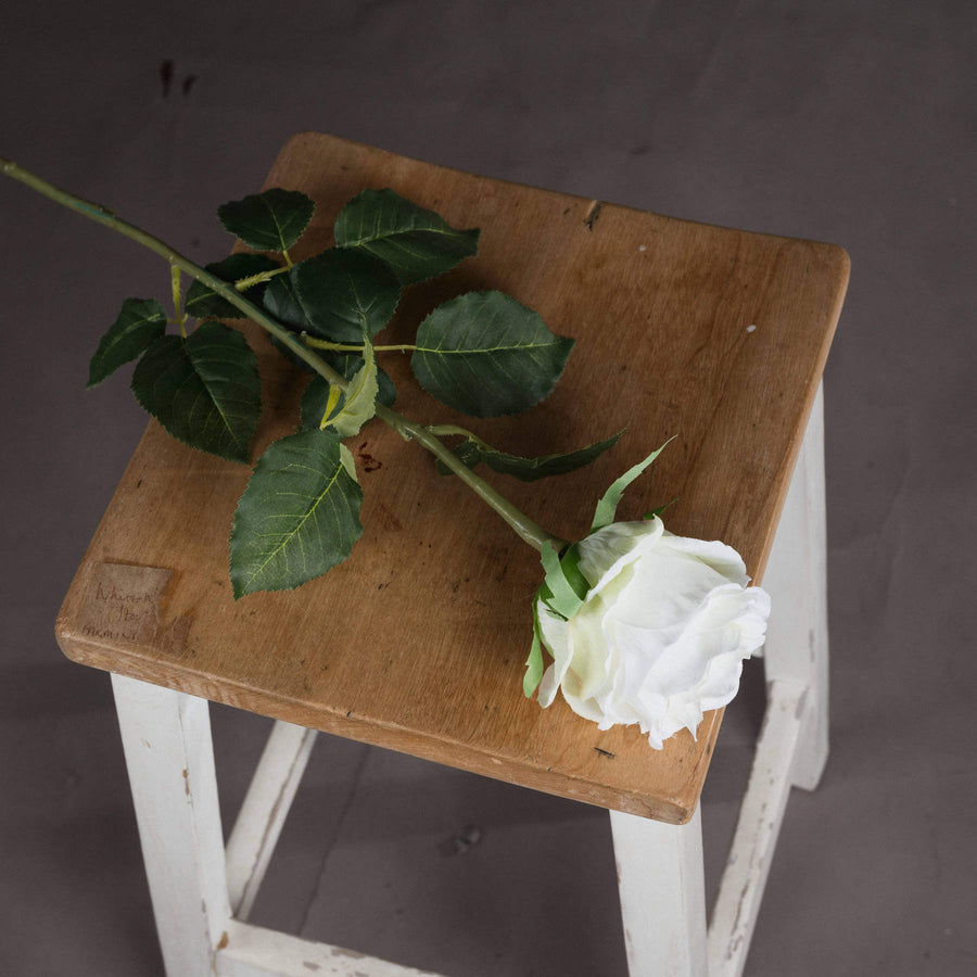 Lifelike white artificial rose stem with realistic petals and green stem, perfect for home decor or floral arrangements. by Sostter at brixbailey.com