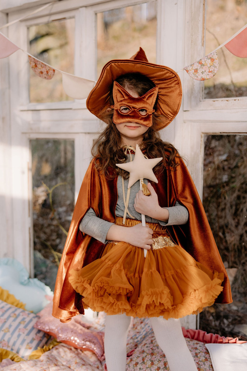 a child laughing, twirling in a ginger velour cape with hand holes for playful adventures