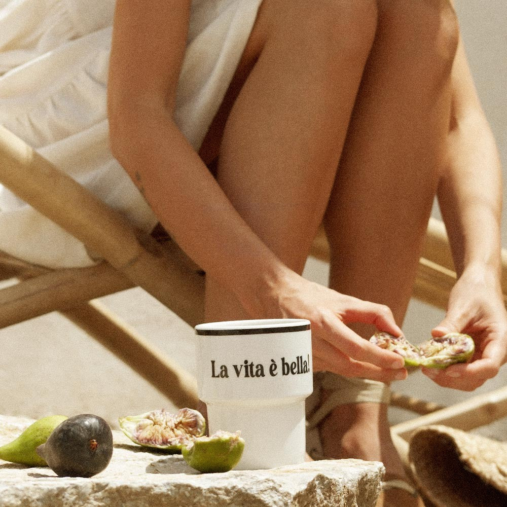 a soft-lit ceramic mug with la vita e bella text on a rustic kitchen counter