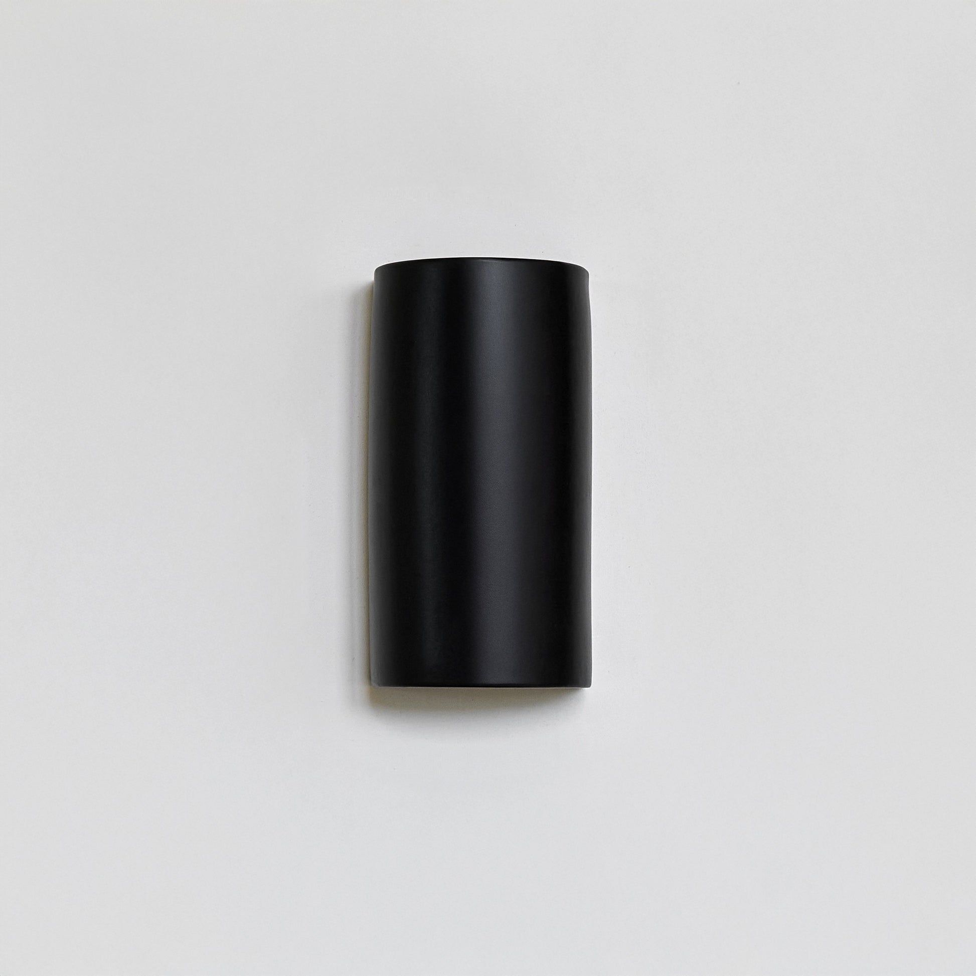 elegant black ceramic wall light casting a cinematic glow on a textured wall