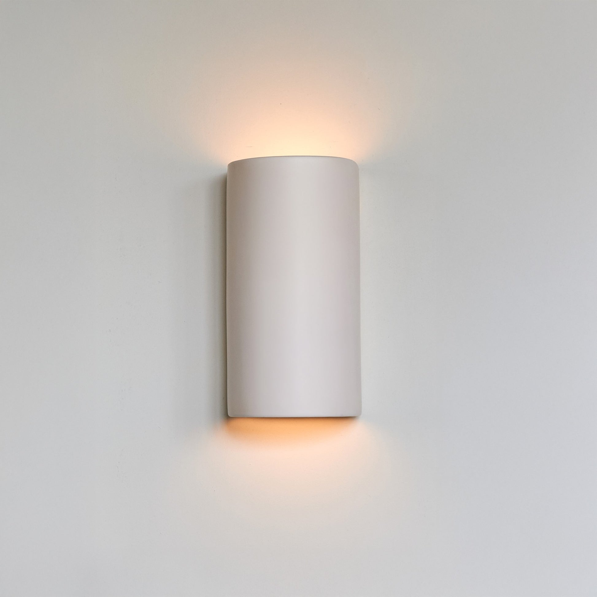 bold off-white ceramic wall light casting a dramatic, cosy glow on a dark wall