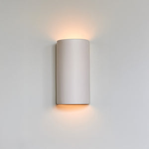 bold off-white ceramic wall light casting a dramatic, cosy glow on a dark wall