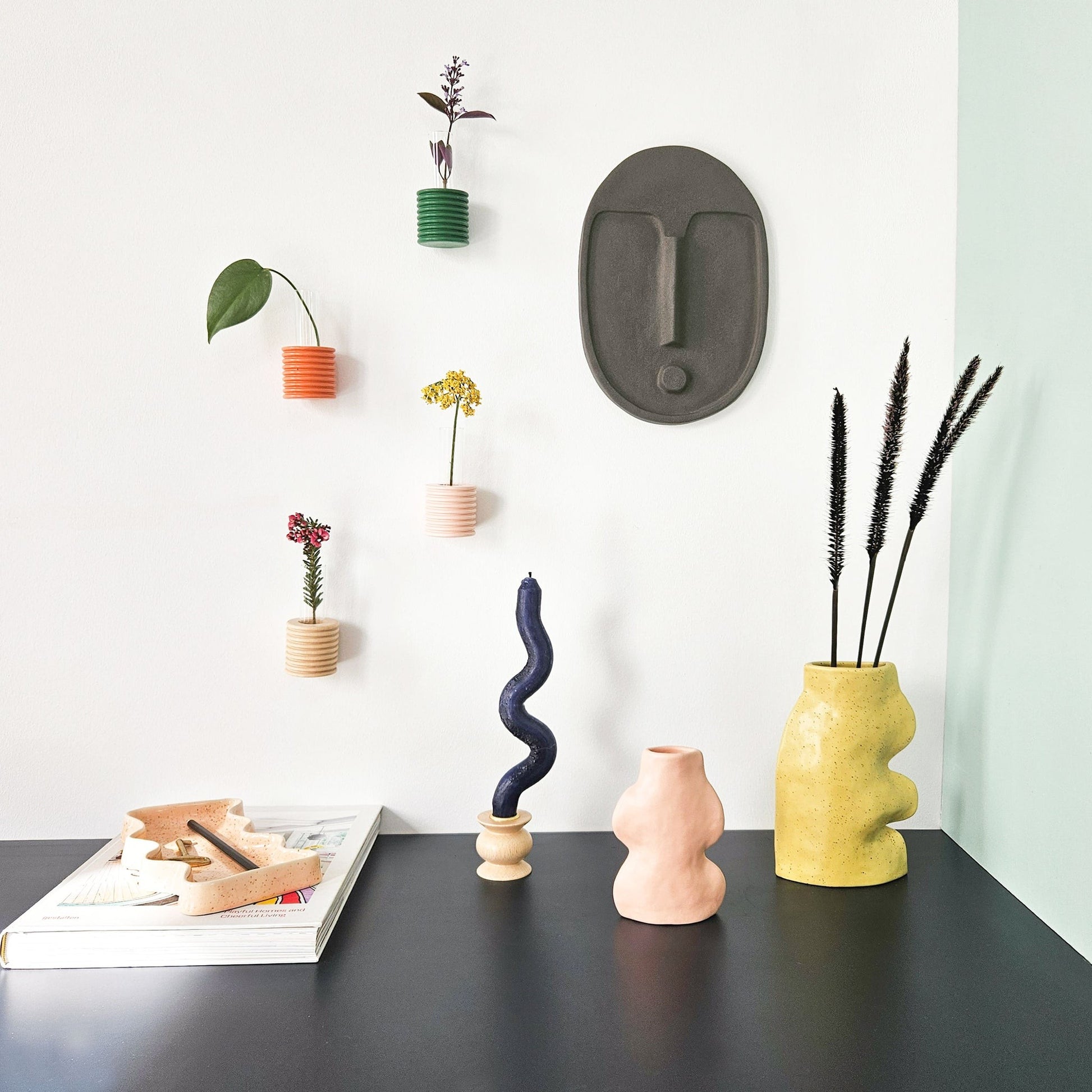 playful anthracite grey ceramic wall mask with textured terracotta glaze, angled to catch warm light