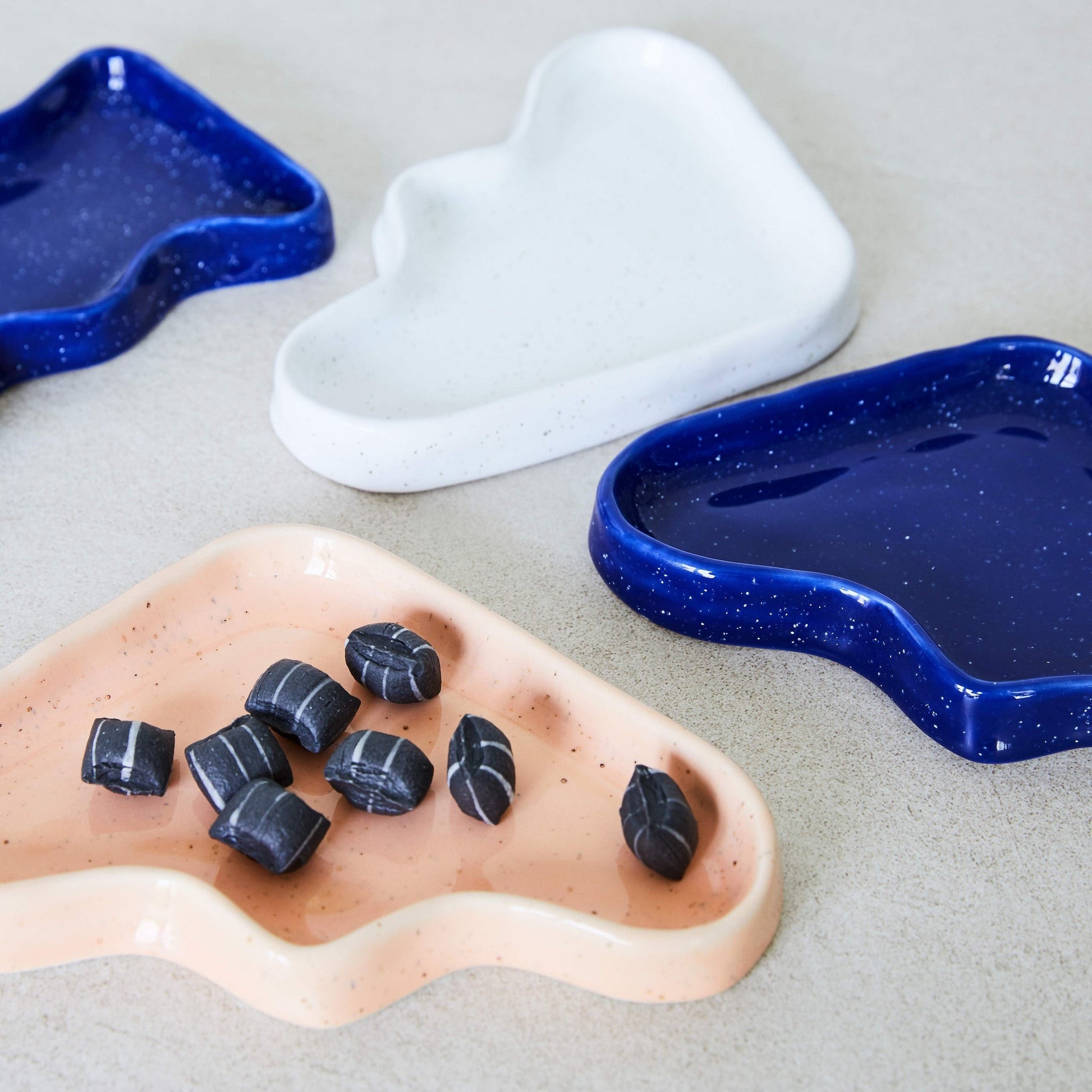 elegant peach ceramic wave tray with speckled glaze, displayed on a marble surface with soft lighting