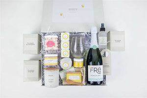 softly lit celebration gift box with grapefruit soap, a plush gray towel, and a scented candle for a comforting home spa