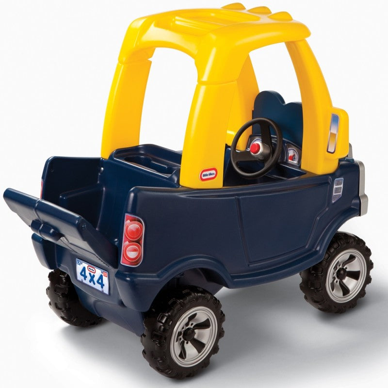 smiling toddler playing with the yellow and black cozy truck ride-on toy indoors