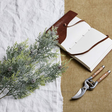 Lifelike frosted pine stem arrangement with crystalline-dusted needles and natural pinecones for winter decor  by Sostter at brixbailey.com