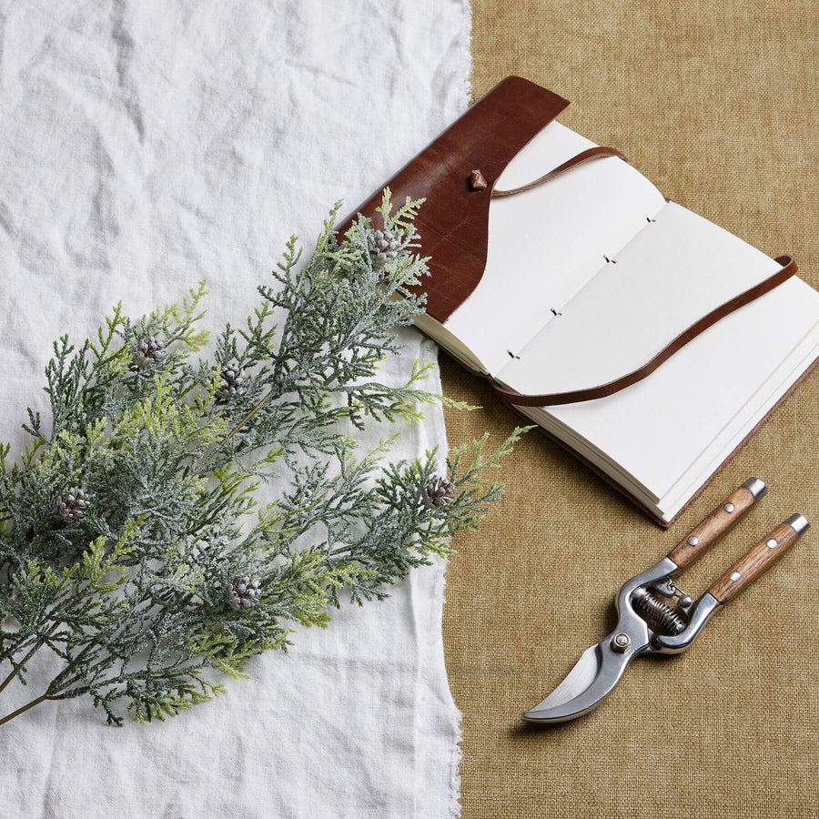 Lifelike frosted pine stem arrangement with crystalline-dusted needles and natural pinecones for winter decor  by Sostter at brixbailey.com