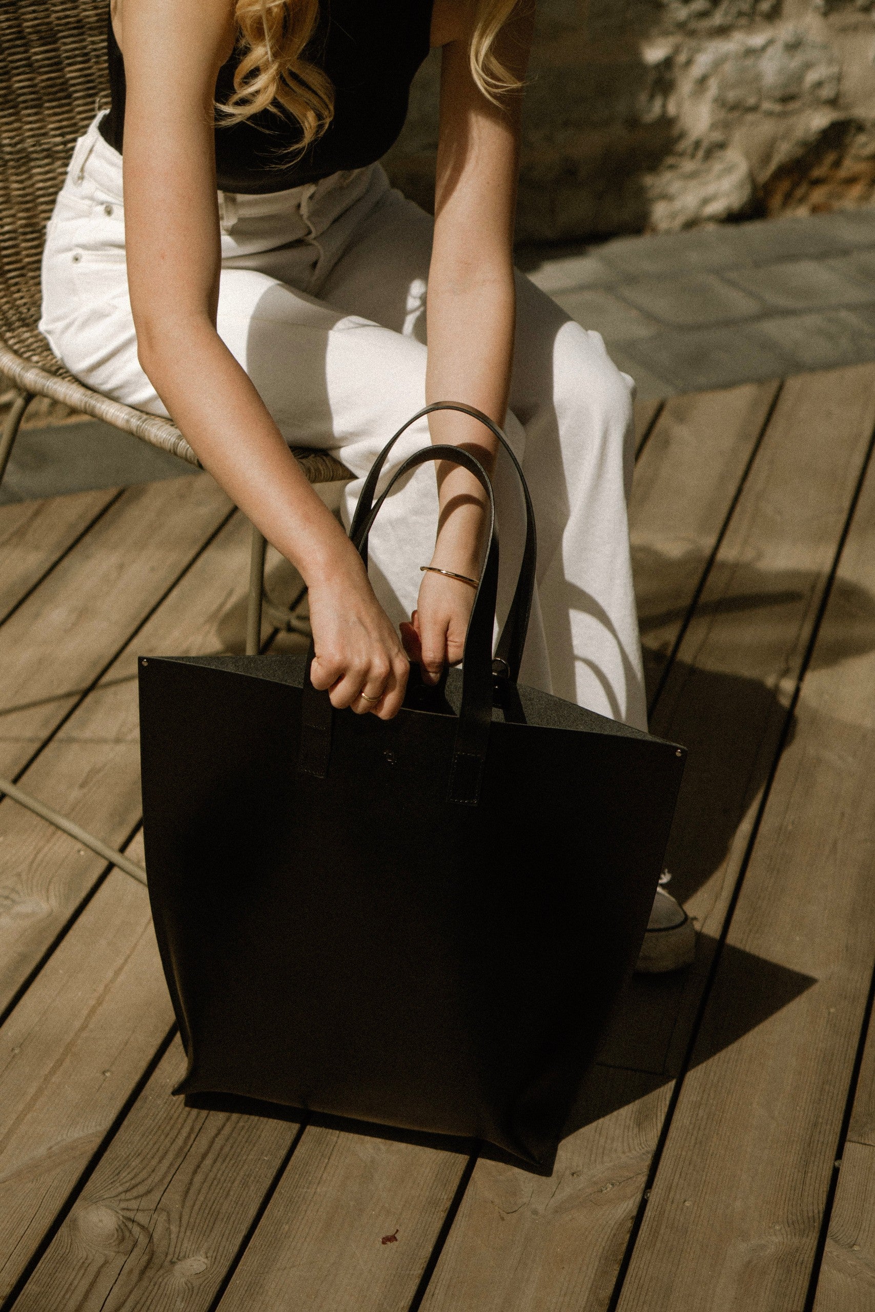 bold black leather bucket bag with structured base and magnetic closure, held confidently by hand