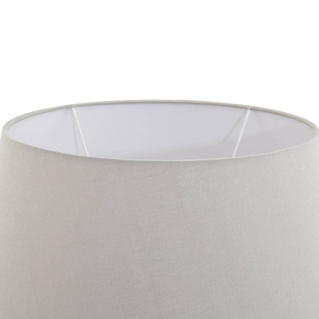 Stone-effect ceramic lamp with light grey fabric shade, hand-finished textured base, and warm ambient glow. by Sostter at brixbailey.com
