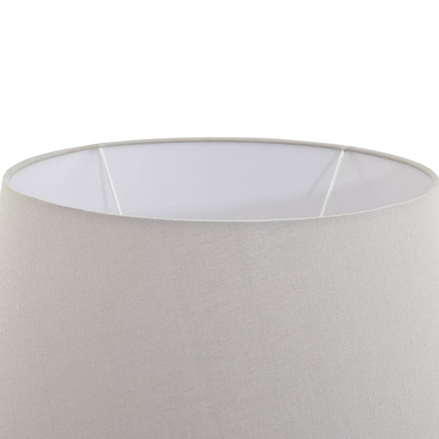 Stone-effect ceramic lamp with light grey fabric shade, hand-finished textured base, and warm ambient glow. by Sostter at brixbailey.com