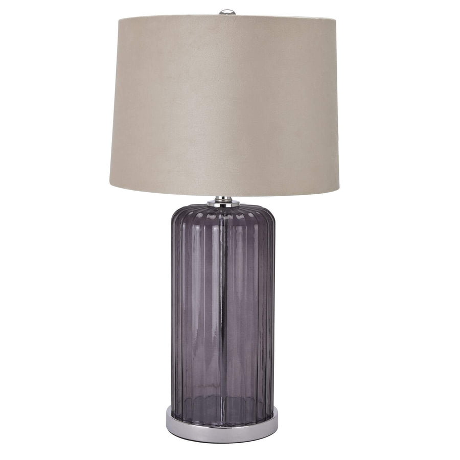 Metallic glass table lamp with fluted texture and beige velvet shade, casting warm ambient light in modern interiors. by Sostter at brixbailey.com