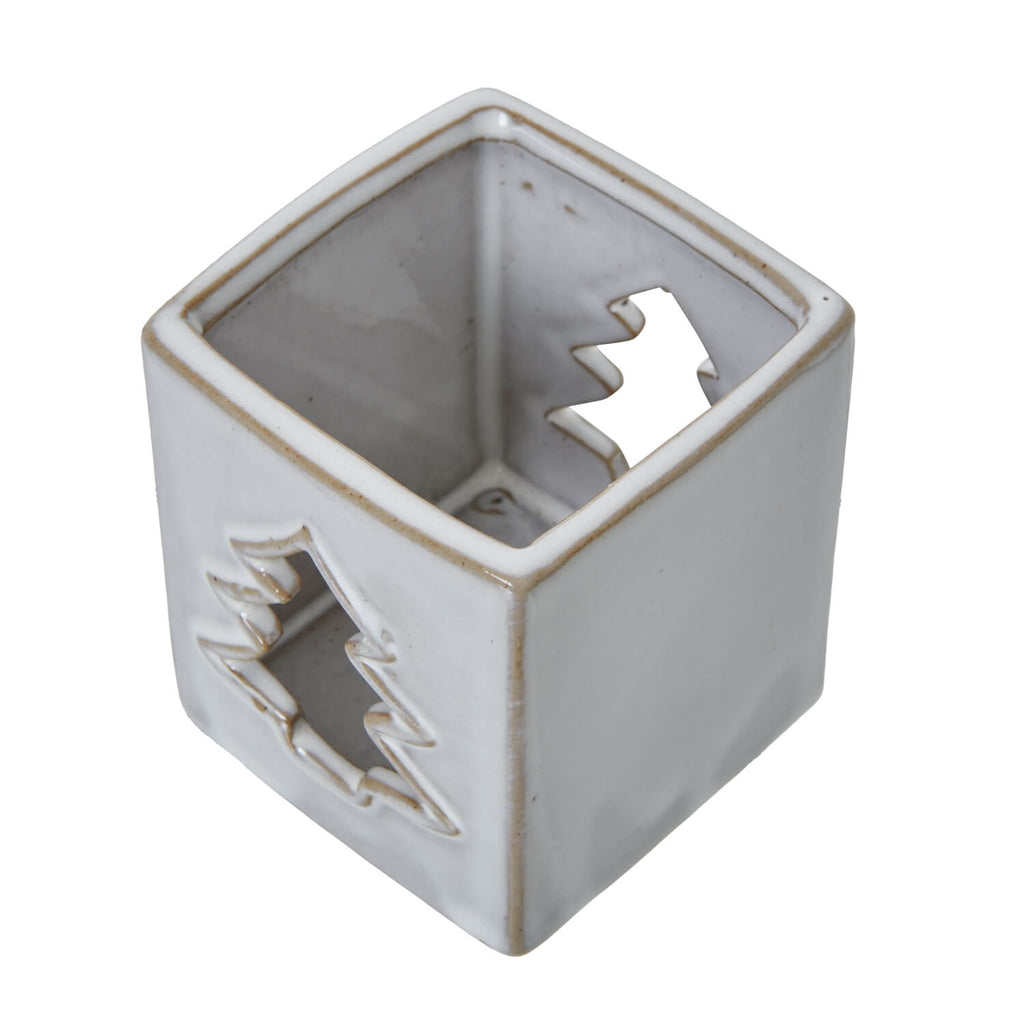 White ceramic tealight holder with intricate tree cut-outs casting warm glow patterns, minimalist home decor by Sostter at brixbailey.com