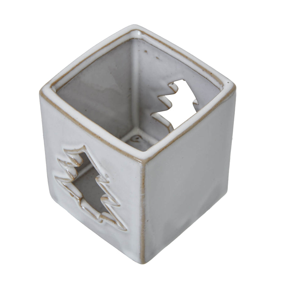 White ceramic tealight holder with intricate tree cut-outs casting warm glow patterns, minimalist home decor by Sostter at brixbailey.com