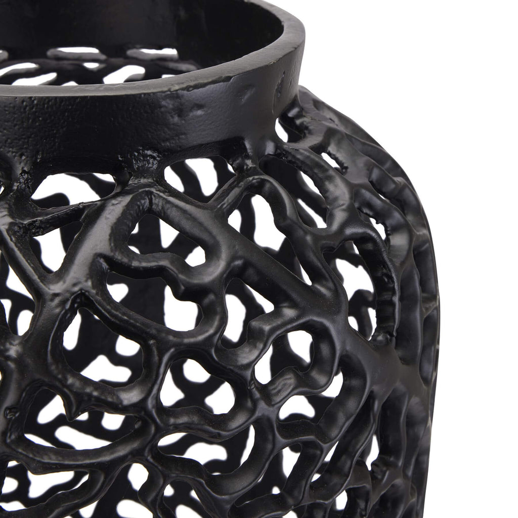 Modern matte black aluminum lattice vase with geometric cutouts, creating dynamic light patterns for contemporary decor. by Sostter at brixbailey.com