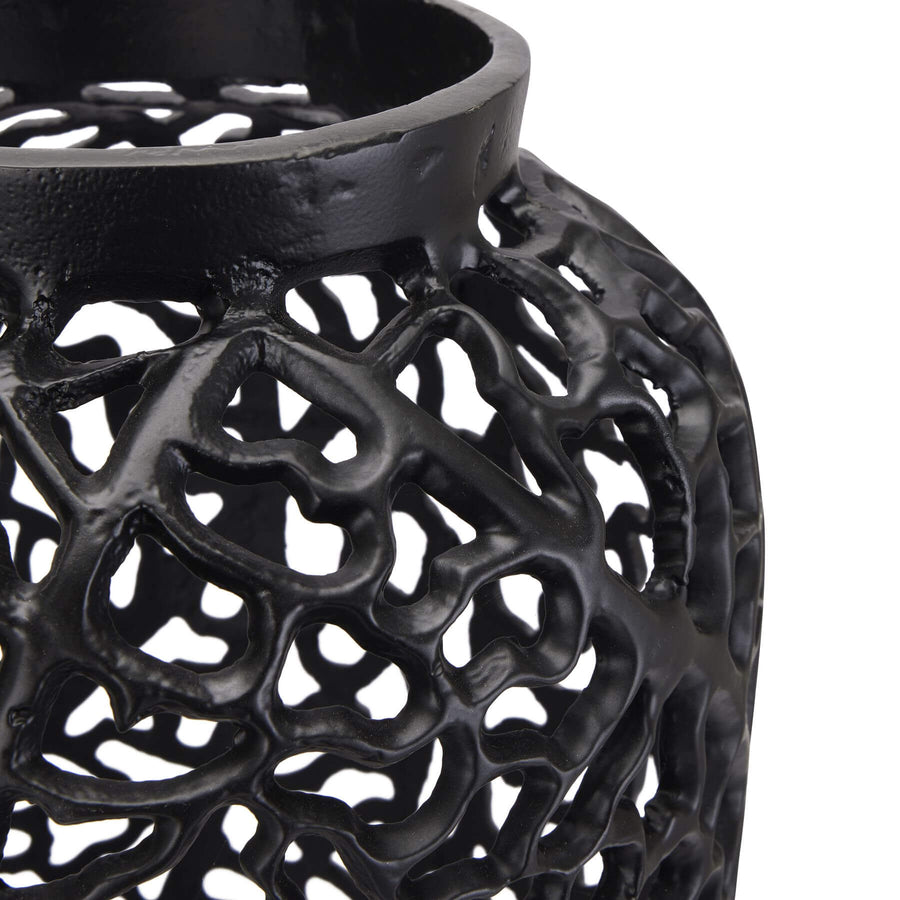 Modern matte black aluminum lattice vase with geometric cutouts, creating dynamic light patterns for contemporary decor. by Sostter at brixbailey.com