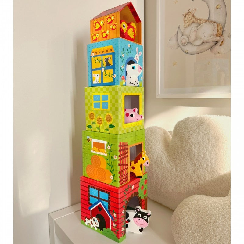 a child's hand stacking a green farm cube puzzle with a wooden cow peeking out