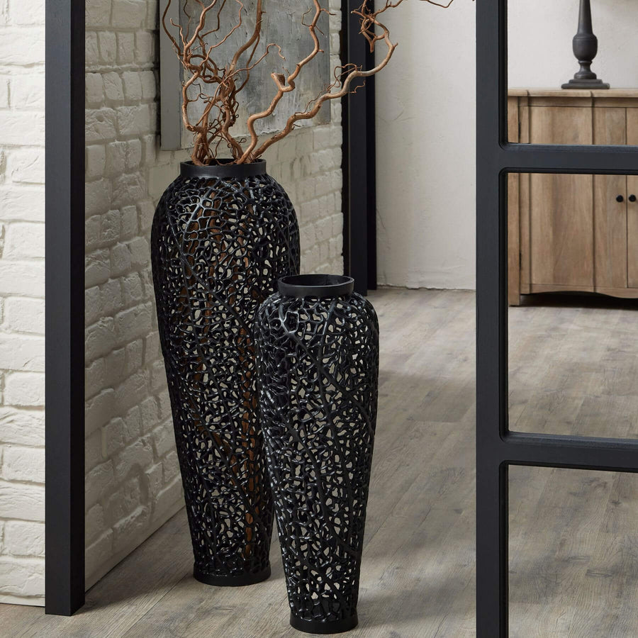 Matte black aluminum lattice vase with geometric cutouts, creating dynamic light patterns in modern interiors. by Sostter at brixbailey.com