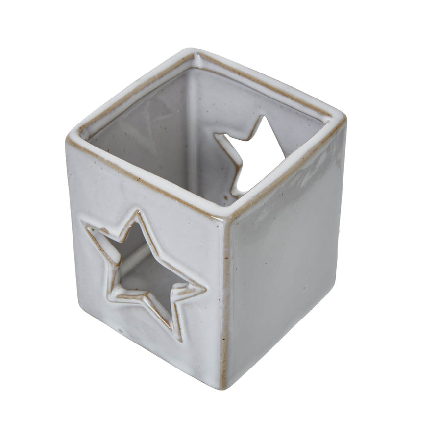 White ceramic tealight holder with star cut-outs casting delicate light patterns, minimalist home decor by Sostter at brixbailey.com