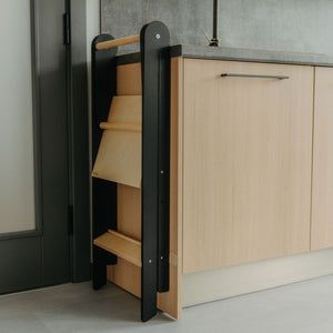 a soft-lit kitchen scene with a child safely standing at the counter in their foldable helper tower