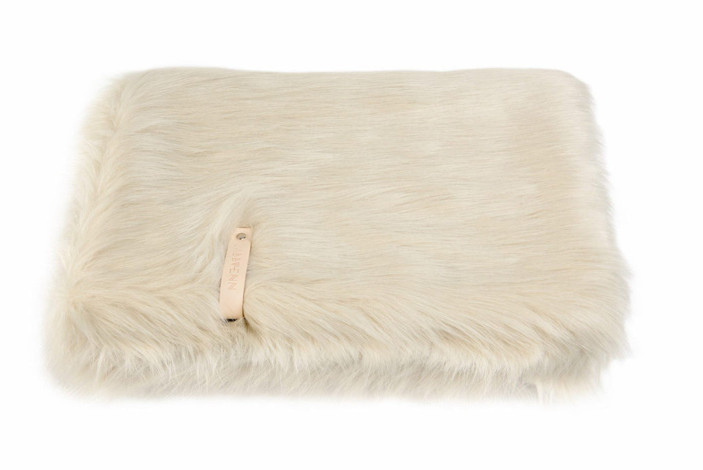 a soft white föra blanket with a leather belt detail, draped invitingly over a pet bed