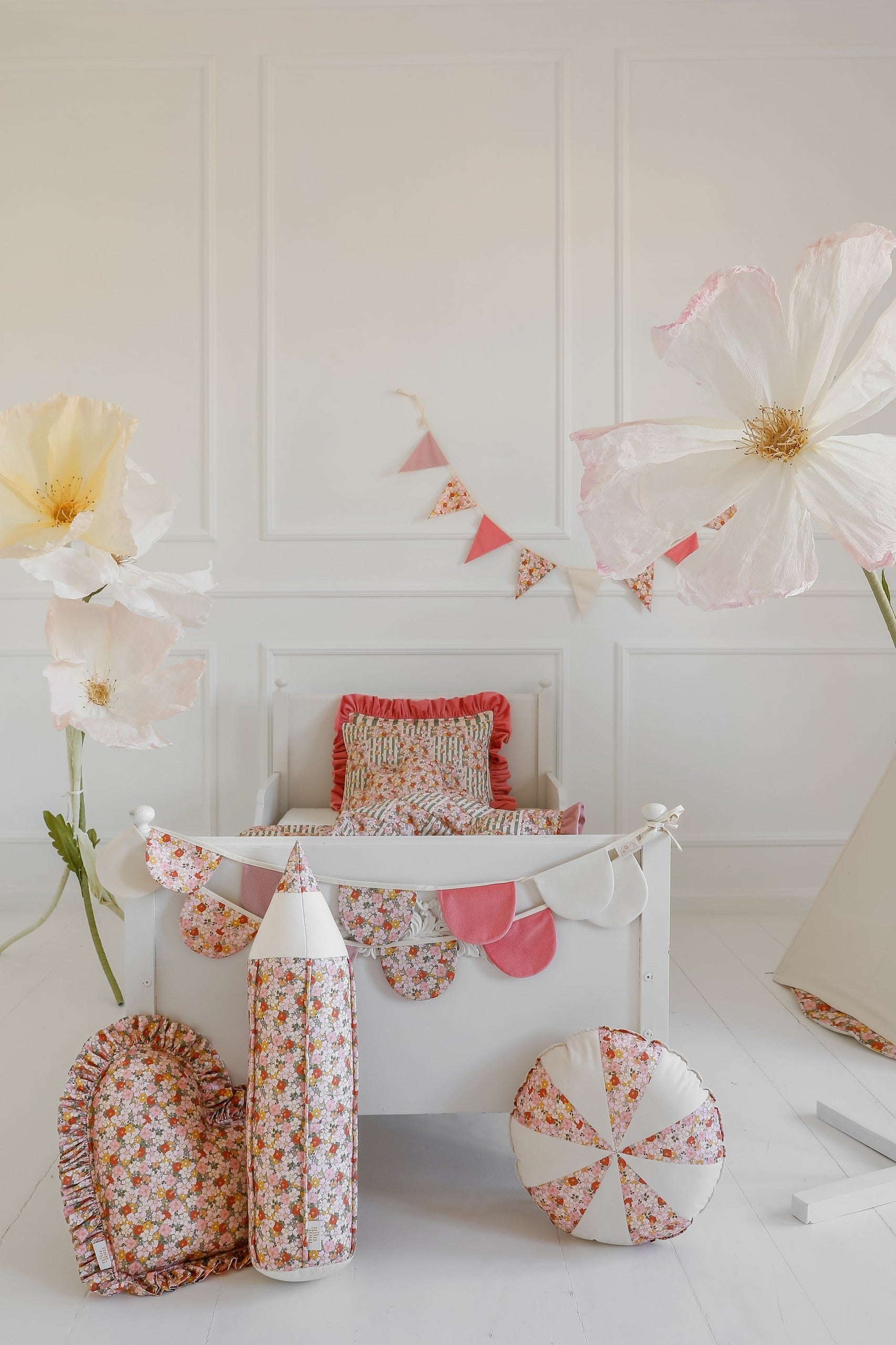 playful birthday garland in garden theme with cotton and velvet pendants, hanging over a child's bed in soft sunlight