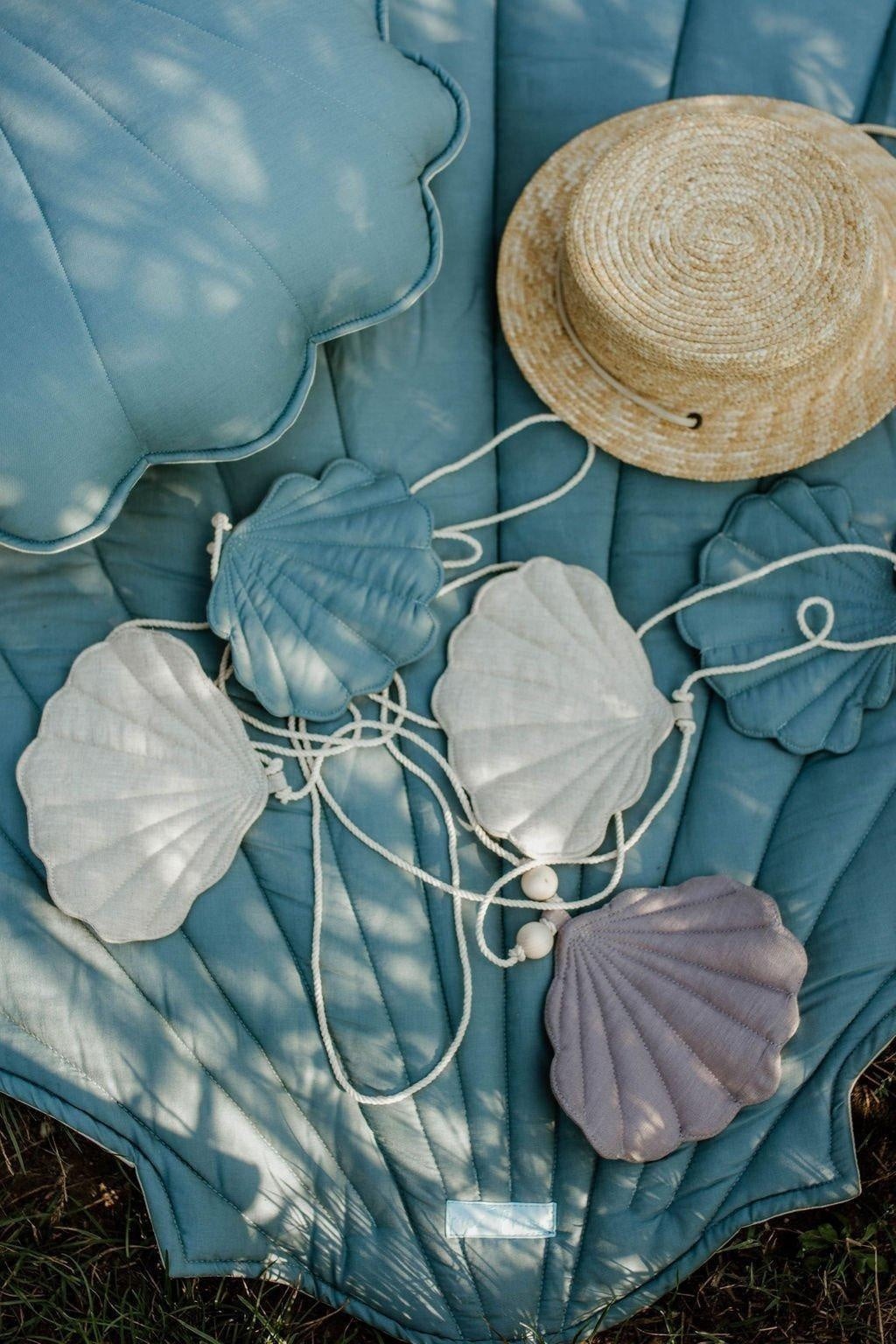 soft dusty blue shell garland draped gently on a sunlit windowsill