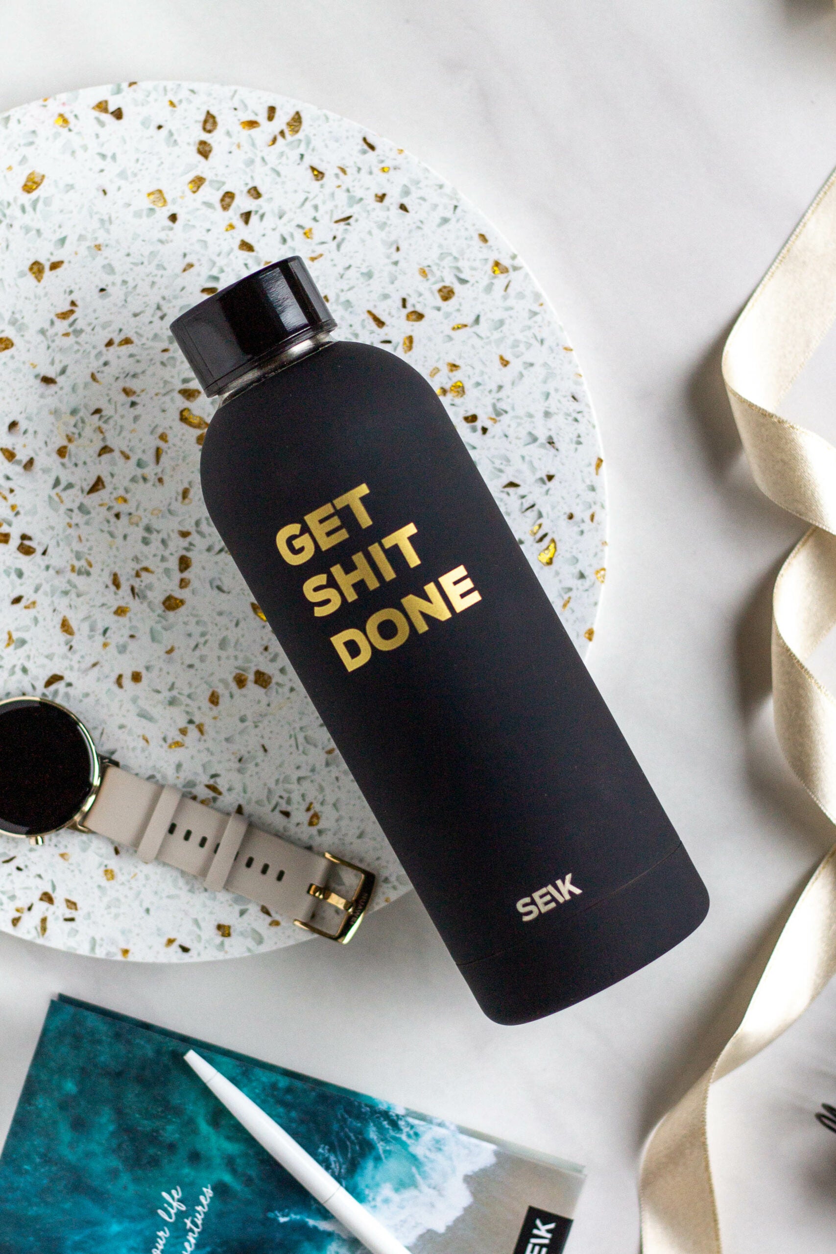 softly lit black seik water bottle resting on a cozy wooden desk