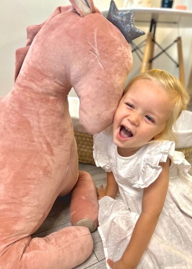 a soft dusty pink velvet pegasus toy in warm nursery light, perfect for a baby shower gift