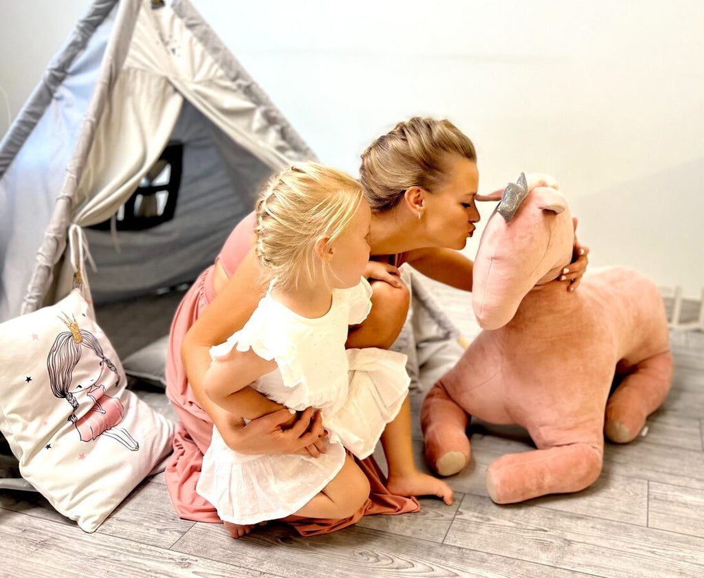 a playful dusty pink velvet peasus toy in a sunny nursery ready for a tea party