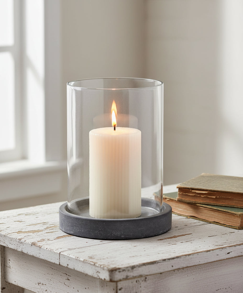 Clear glass candle holder with a gray base on a white background