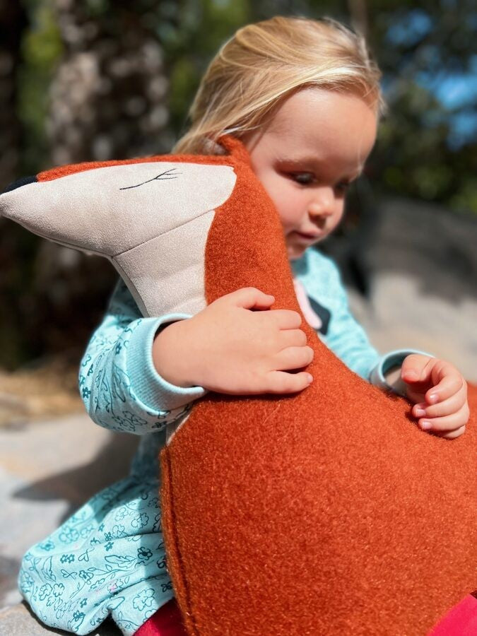 a handmade forest fox pillow in soft red felt, side-lit with a gentle, comforting glow