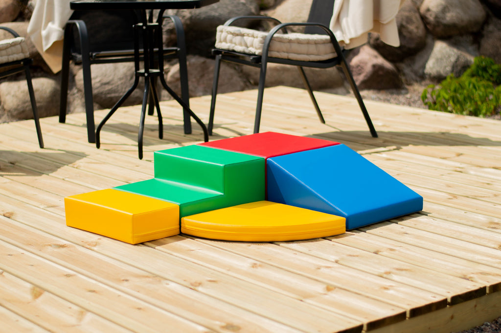 a child's hand reaching for the top of the vibrant multicolor iglu foam corner climber