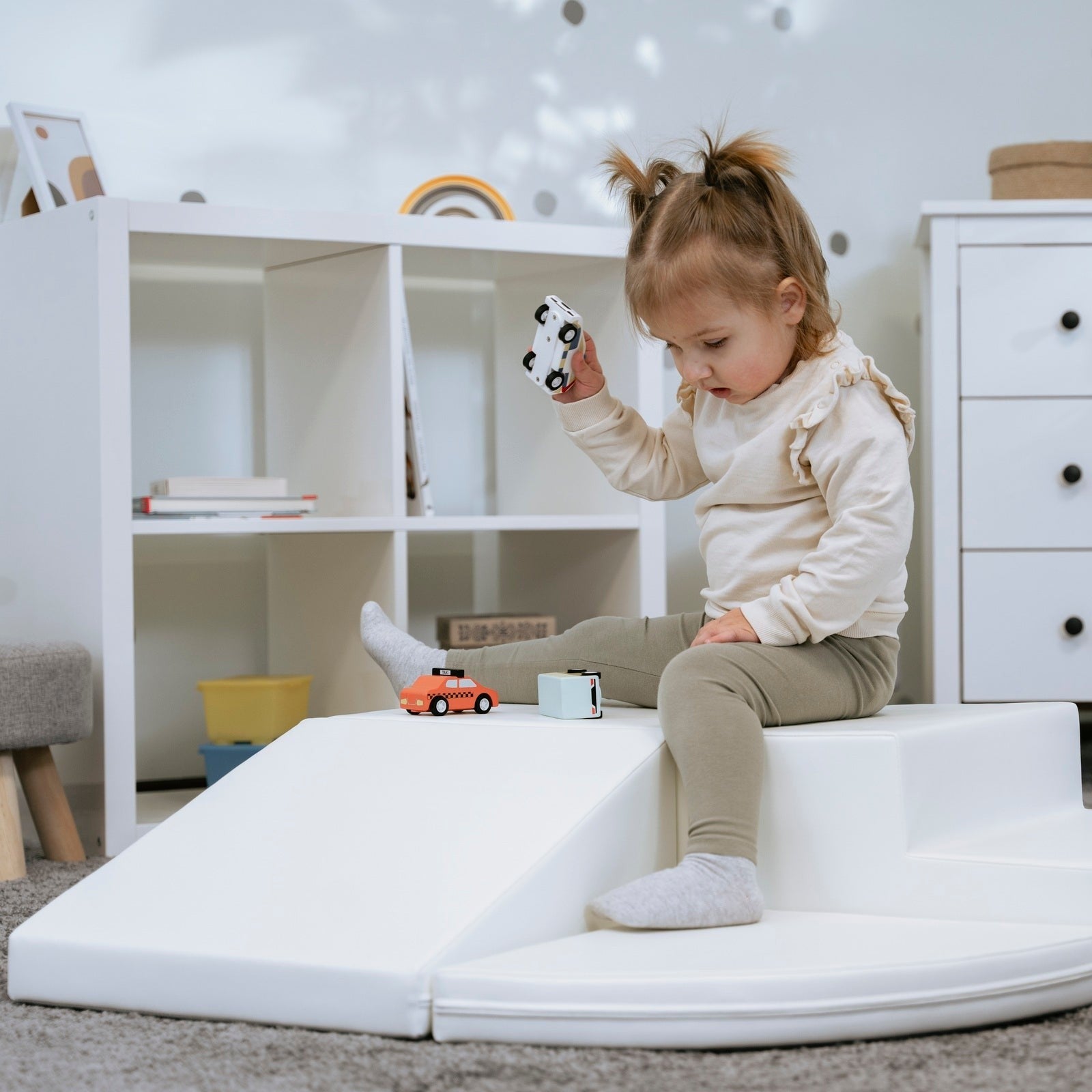 a child's hand reaching for the top of a soft white corner climber block