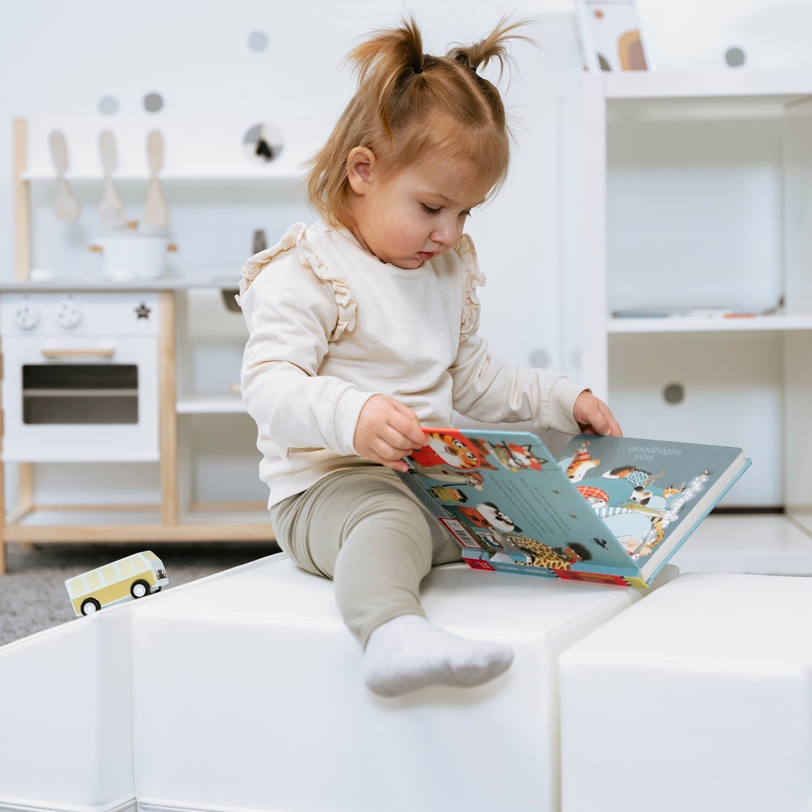 a toddler carefully balancing on a white foam corner climber during imaginative play