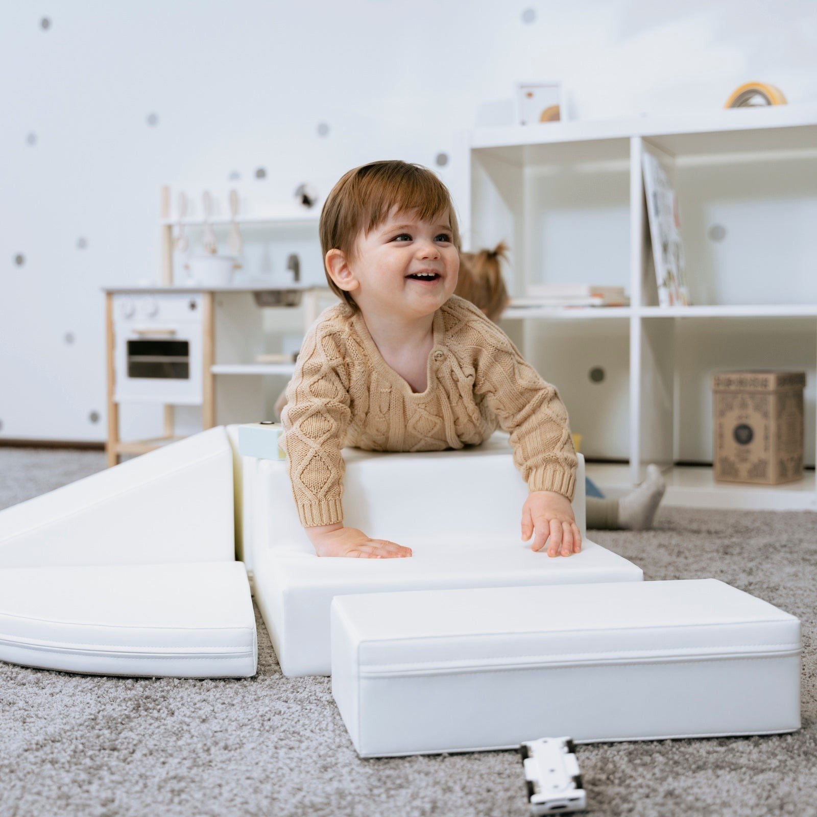 child building a creative corner climber fort with soft white foam blocks