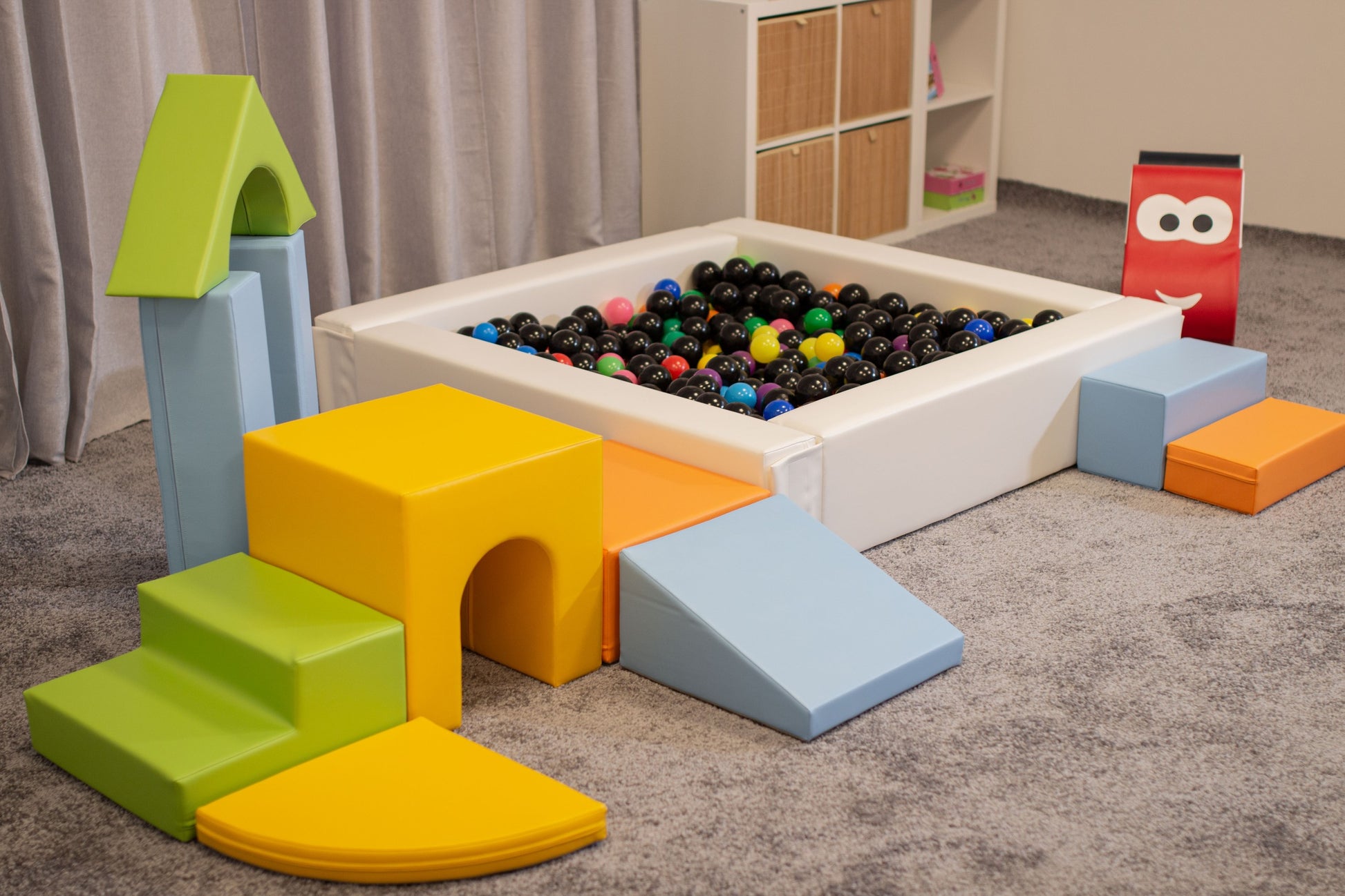 a child's hand placing a vibrant blue iglu foam block onto a colorful fort structure