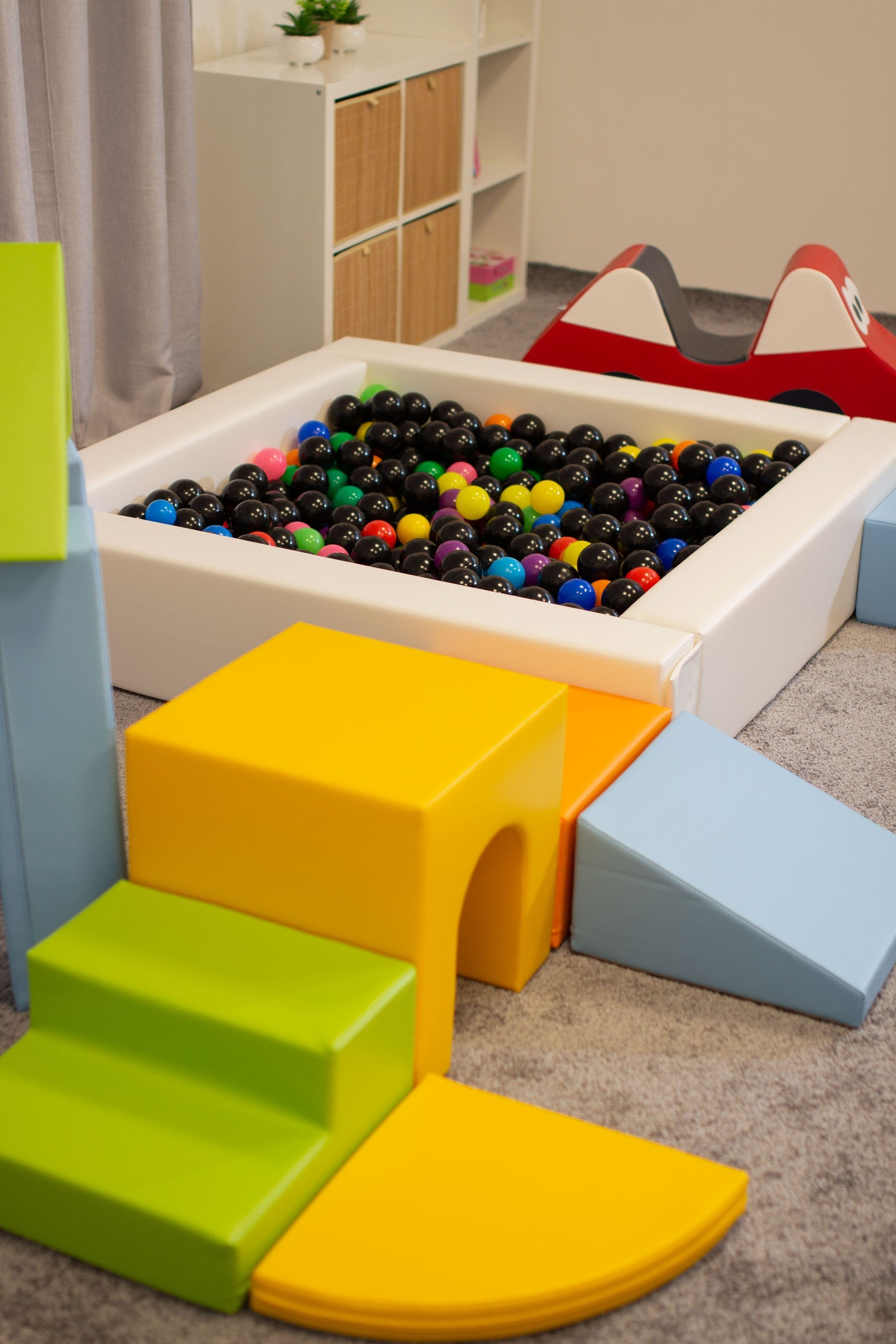 a child's hand placing a vibrant blue iglu foam block on a sunlit castle structure