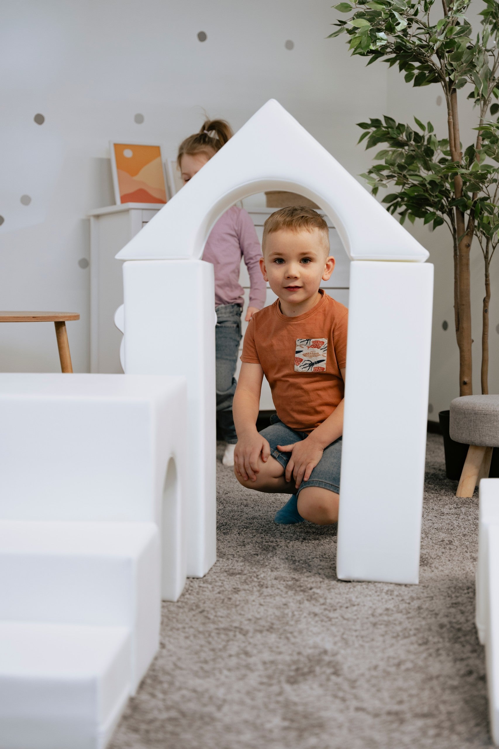 a child's hand building a creative igloo with soft white foam blocks