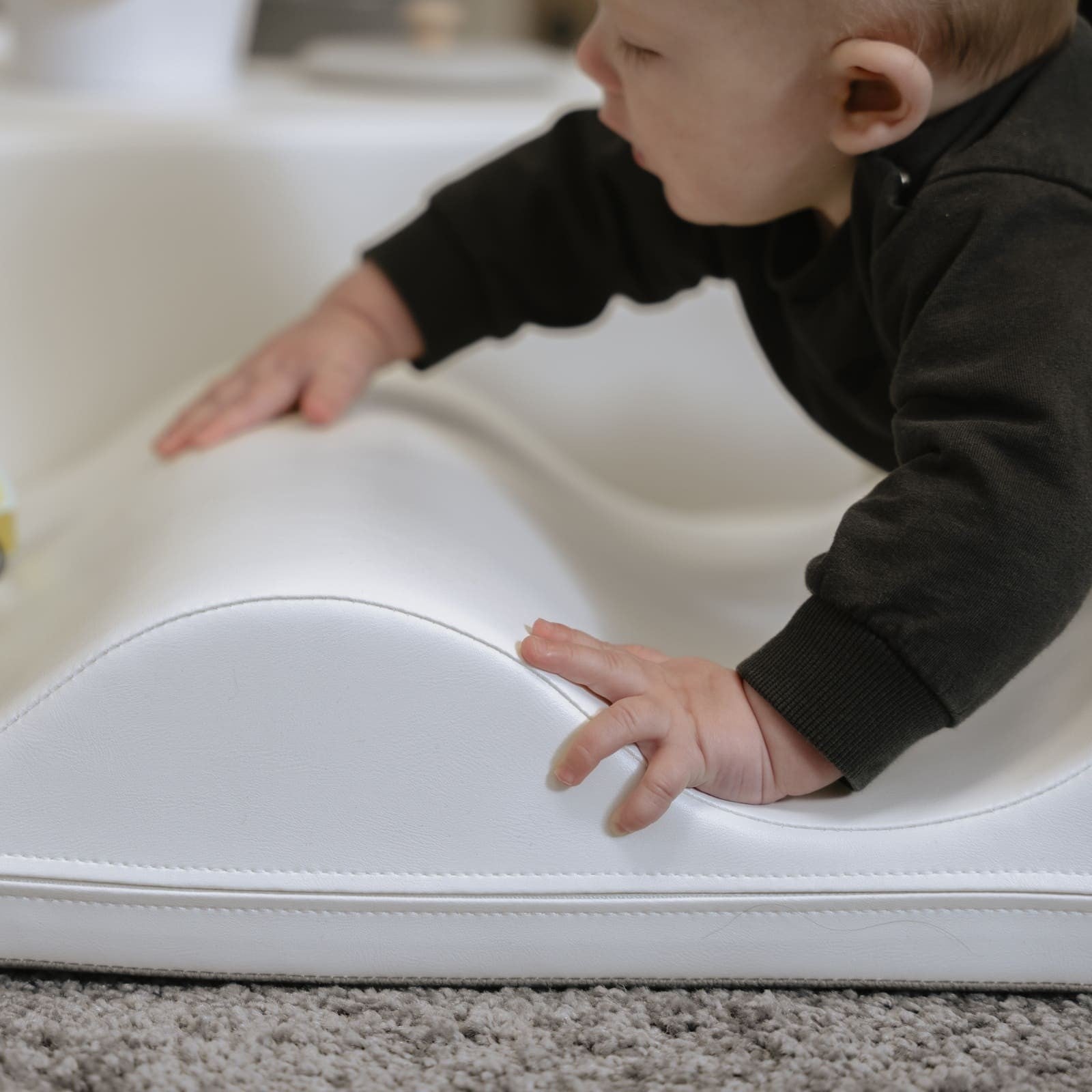 a child's hand reaching for a soft white iglu foam block on a clean floor