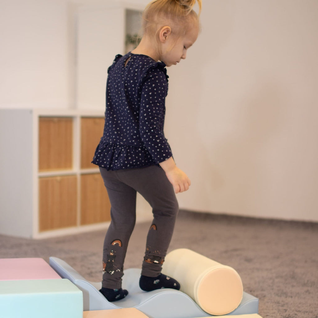 toddler laughing as they build a pastel foam block fort for imaginative play