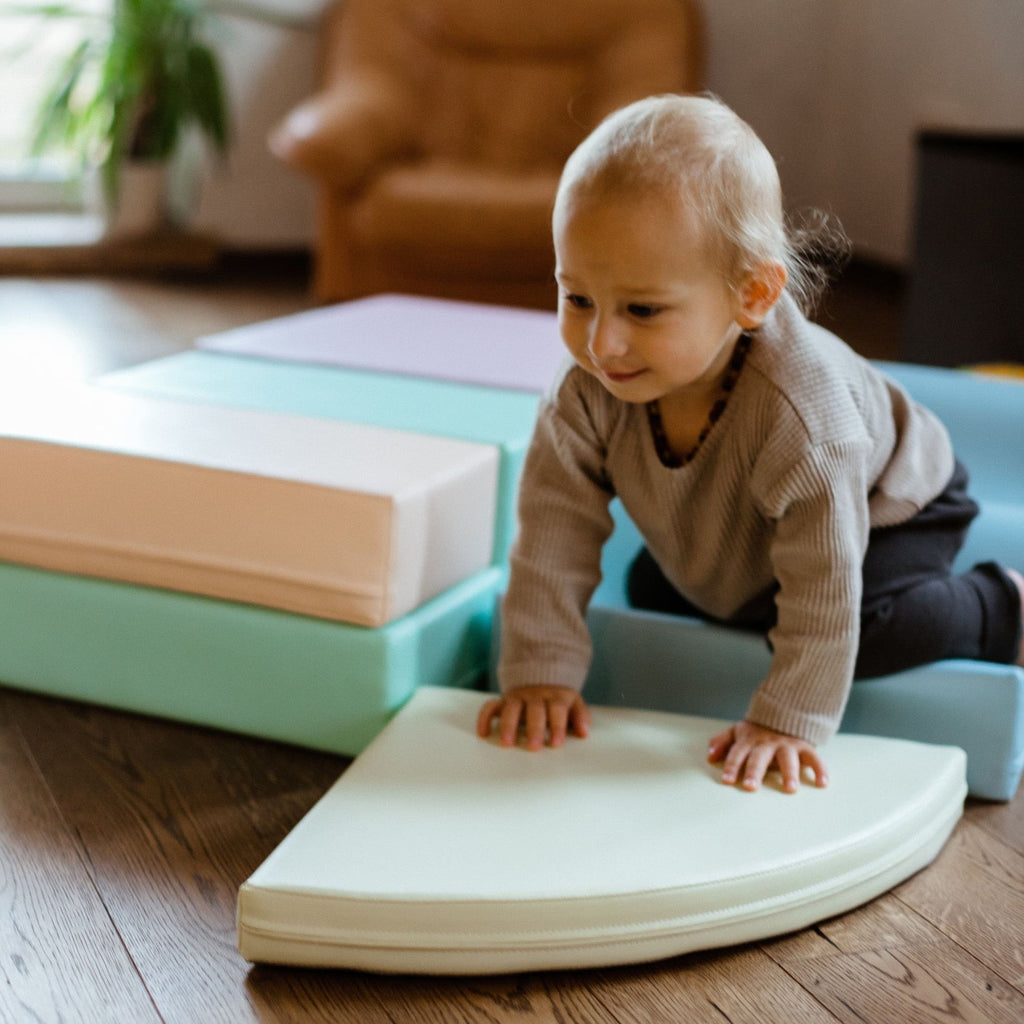 a toddler building a soft pastel foam block fort in a sunlit playroom