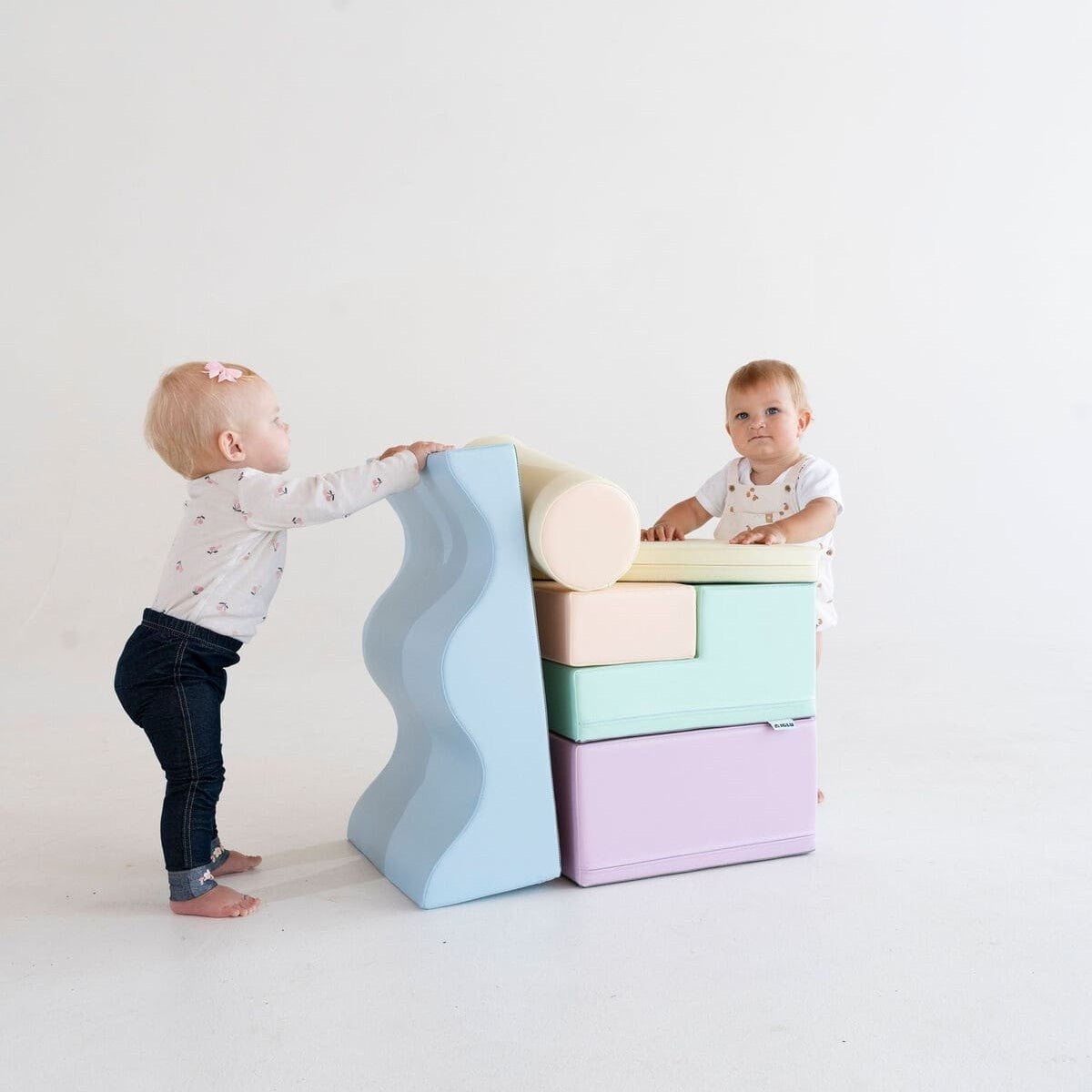a toddler building a cozy pastel foam block fort in a sunlit playroom