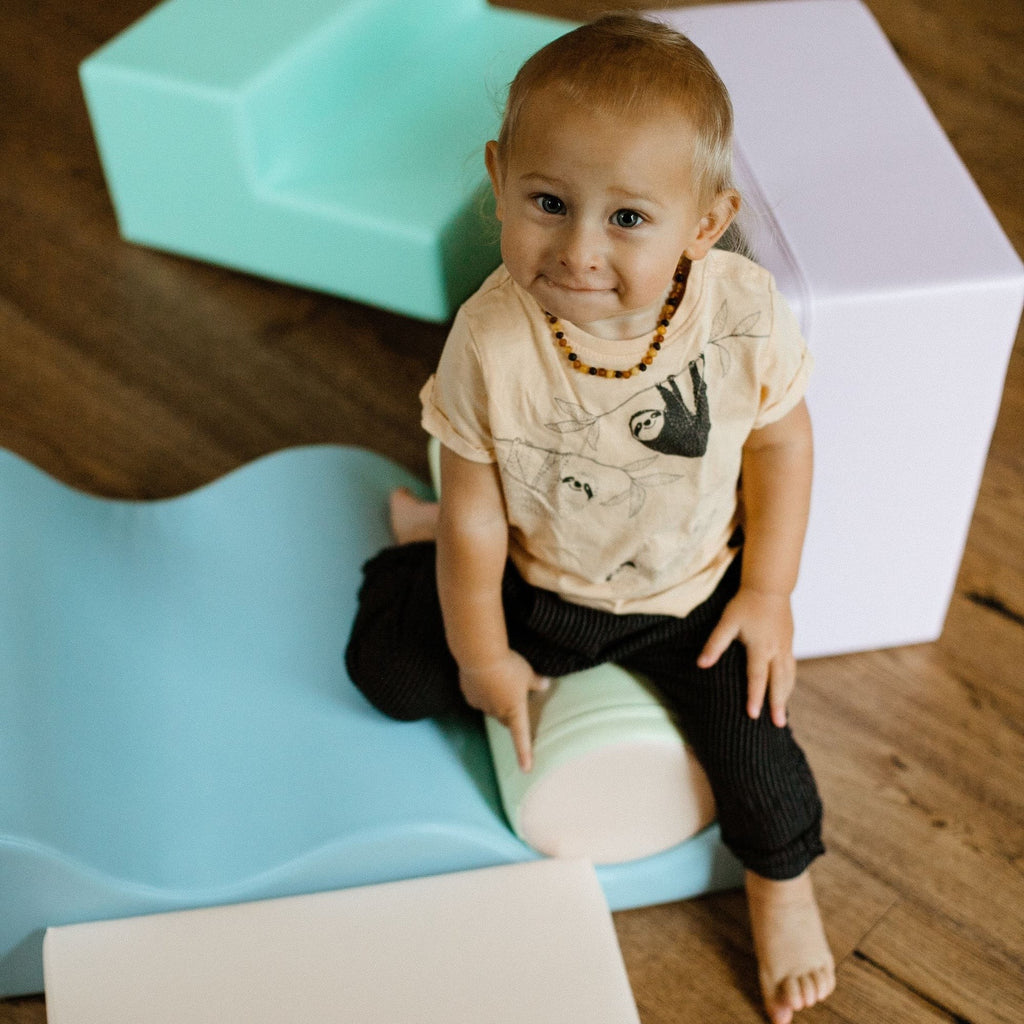a toddler's hand building a soft pastel igloo from light pastel foam blocks