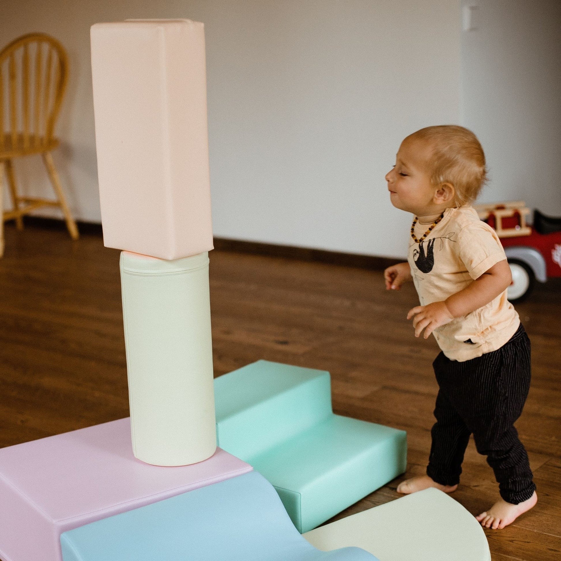 toddler building a soft pastel foam block castle in a sunlit playroom