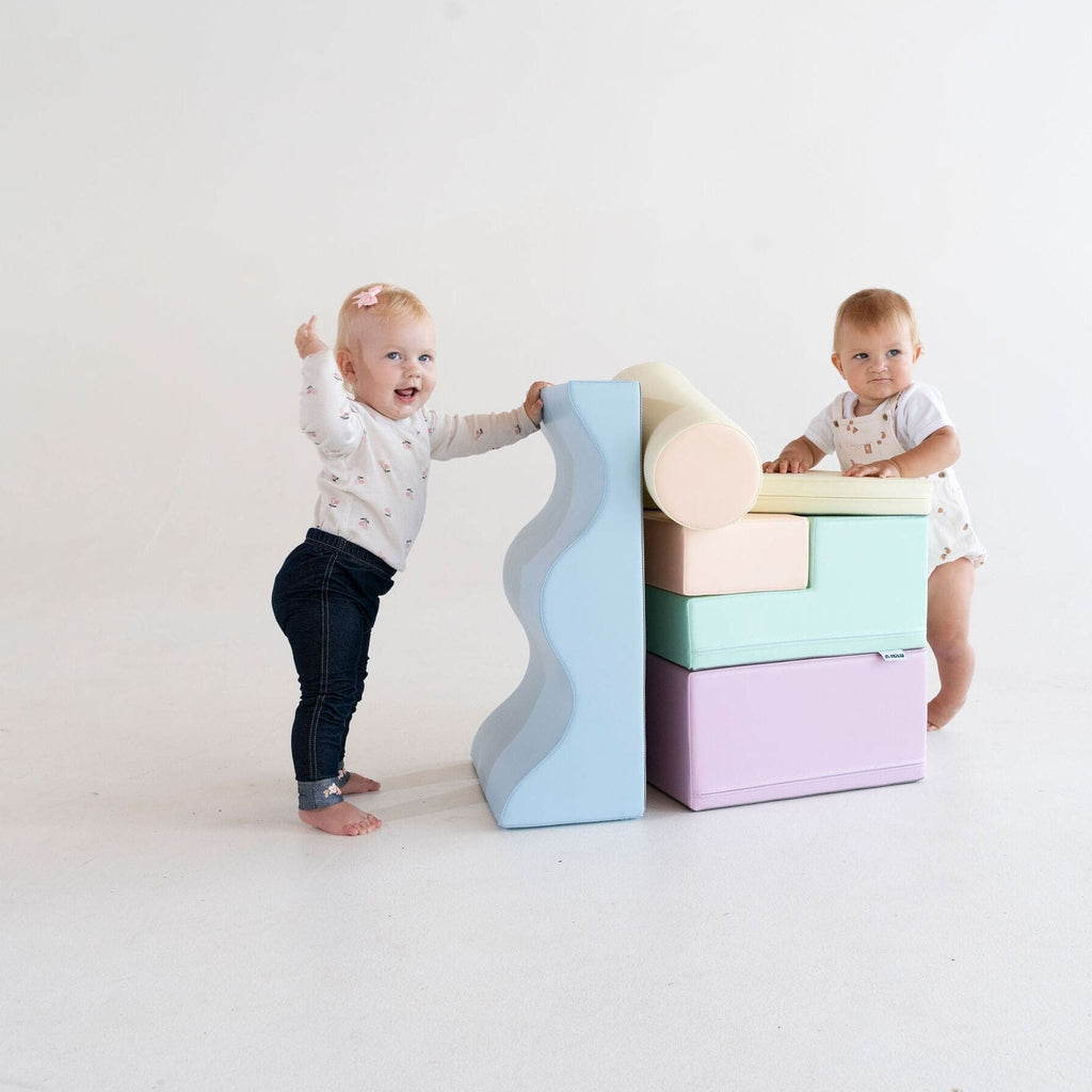 toddler building a soft pastel igloo fort with light pastel foam blocks