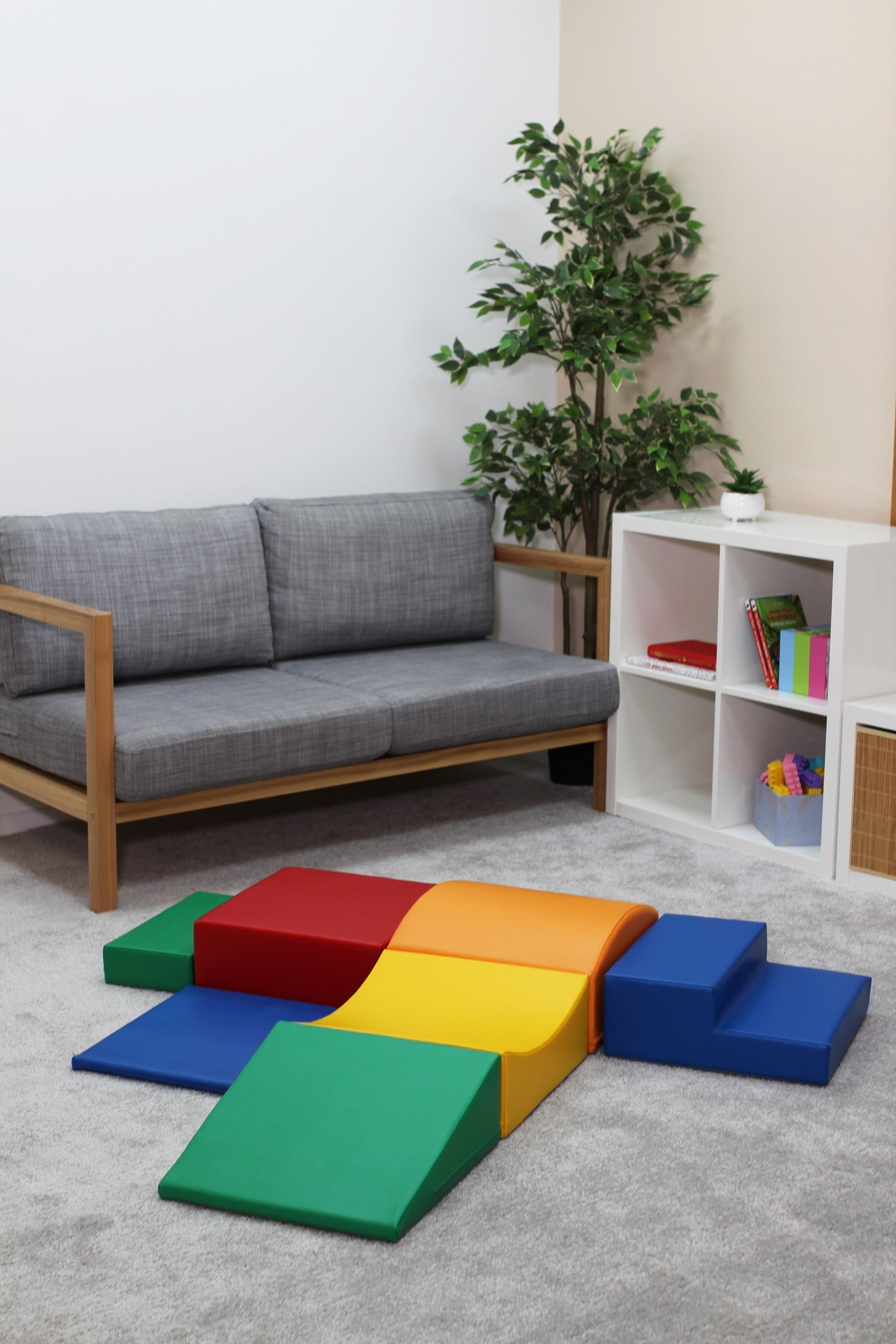 a toddler's small hands stacking a vibrant yellow soft play block on a colorful tower