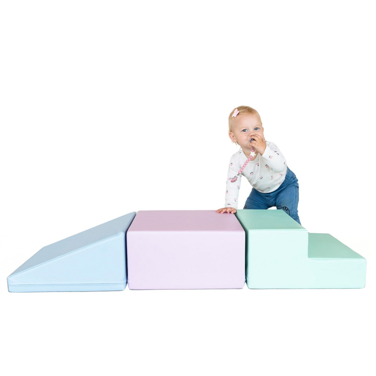 a toddler's hand touching a soft pastel foam block in warm morning light